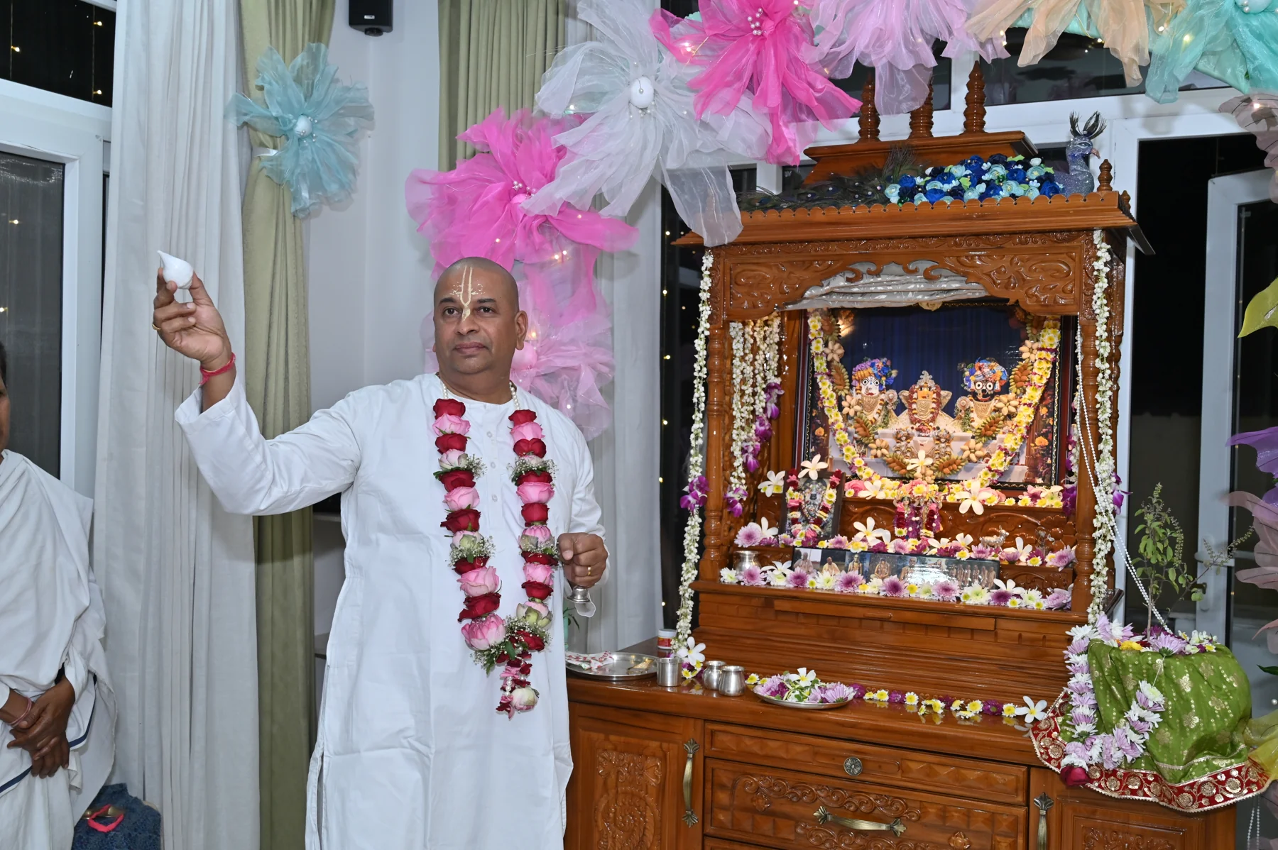 Caitanya Avatāri Dāsa participating in worship beside a decorated shrine